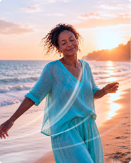 A woman walking freely along the shore at sunset, arms open